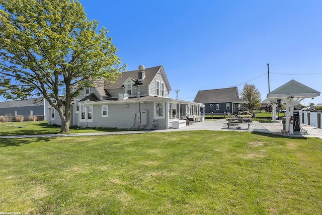 back of house with a yard, a patio, and roof with shingles