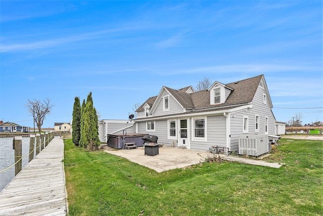 rear view of house featuring a hot tub, a patio area, a lawn, and central AC