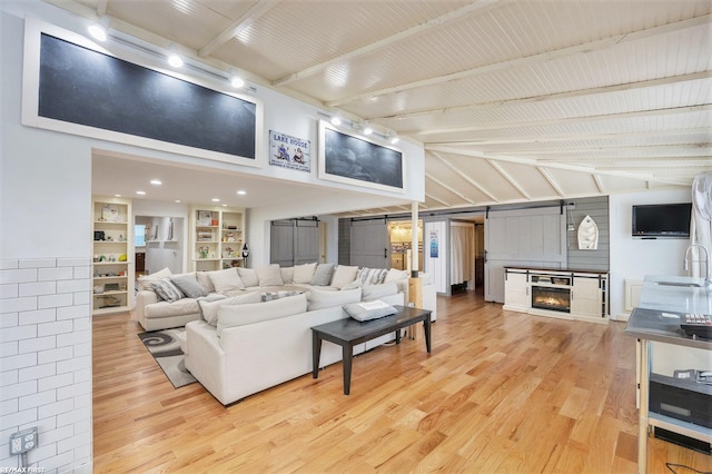living room with wood finished floors, a barn door, and high vaulted ceiling
