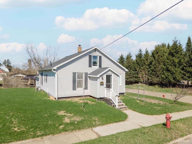 739 N 6th Ave, Iron River, MI 49935 - bungalow-style home featuring a chimney, a front yard, a shingled roof, and central AC unit