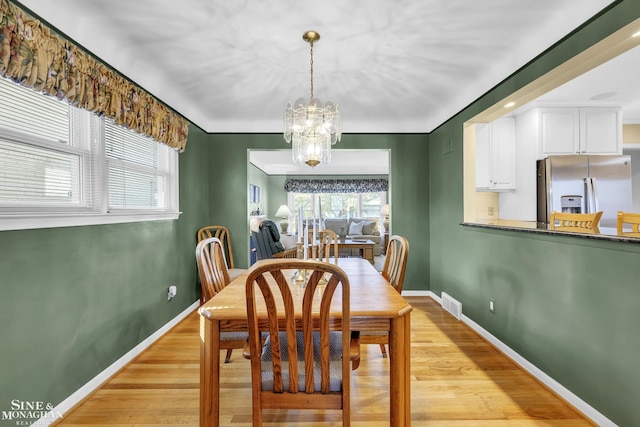 dining room featuring a chandelier, light wood-style flooring, and baseboards