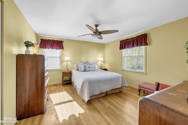 bedroom with multiple windows, baseboards, wood finished floors, and a ceiling fan