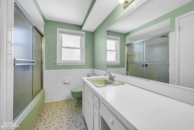 full bath featuring a wainscoted wall, toilet, vanity, tile walls, and tile patterned flooring