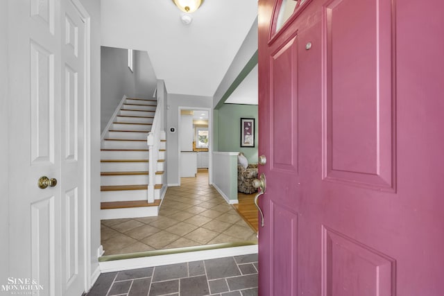 tiled foyer featuring stairs and baseboards