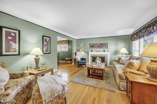 living area featuring light wood-type flooring, a fireplace, and baseboards