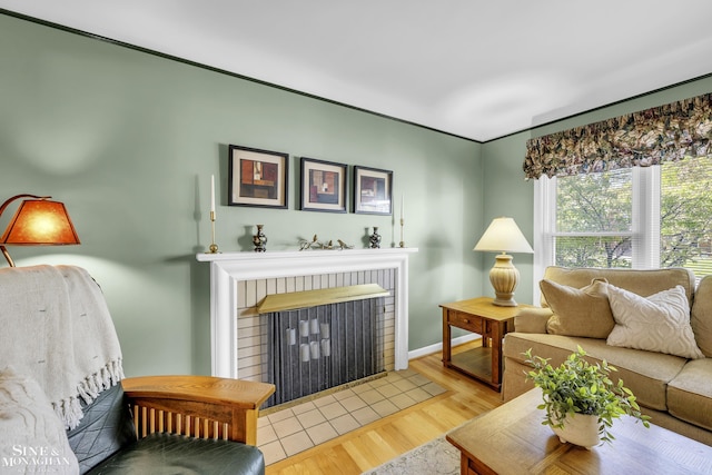 living room with a brick fireplace, wood finished floors, and baseboards
