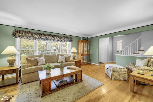 living room with light wood-style flooring, stairs, and baseboards