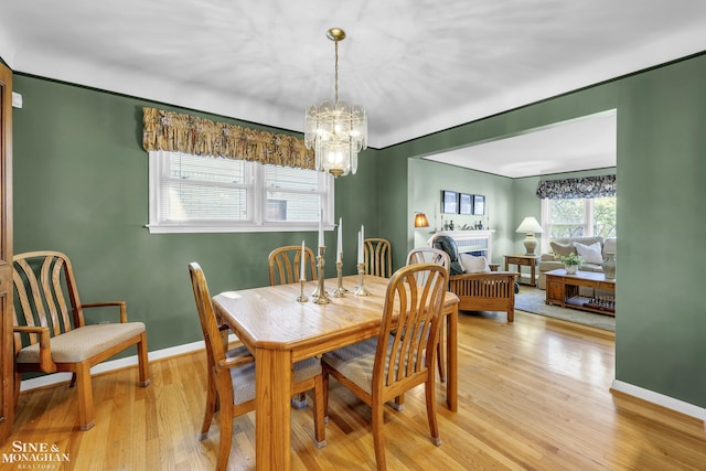dining area with a chandelier, light wood finished floors, and baseboards