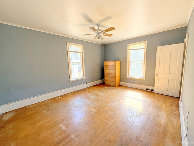 unfurnished room with ornamental molding, ceiling fan, light wood-type flooring, and baseboards
