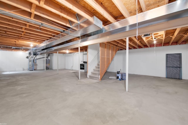 unfinished basement featuring gas water heater, stairway, and heating unit
