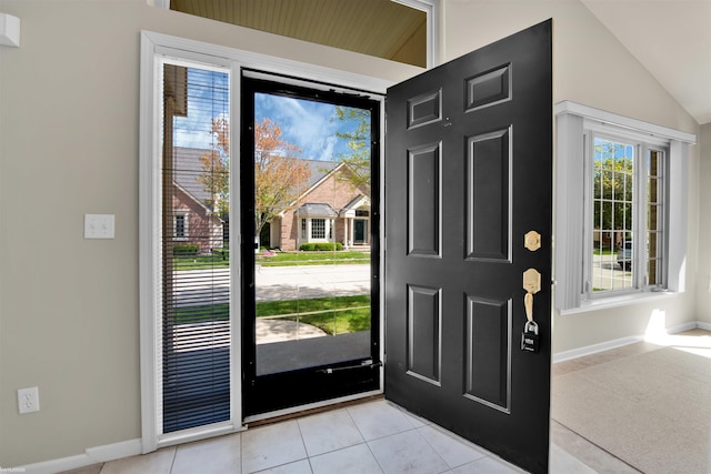 entryway featuring light tile patterned floors, lofted ceiling, and baseboards
