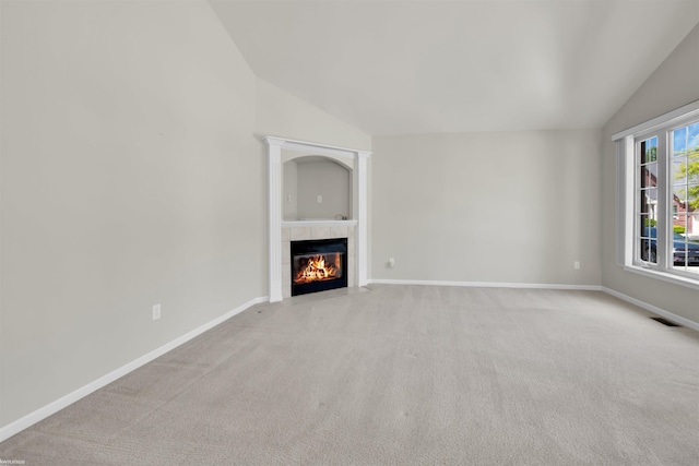 unfurnished living room with vaulted ceiling, light colored carpet, a tile fireplace, and baseboards