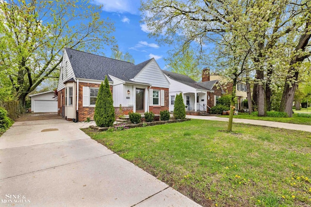 bungalow-style home with brick siding, a front yard, an outbuilding, and covered porch