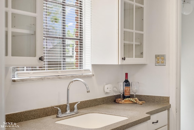 kitchen with a sink, glass insert cabinets, and white cabinets