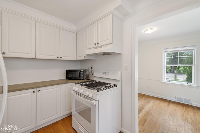 kitchen featuring white gas stove, under cabinet range hood, black microwave, white cabinets, and light wood-type flooring