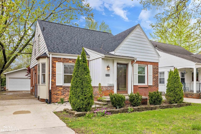 bungalow with brick siding, a shingled roof, an outbuilding, a detached garage, and board and batten siding