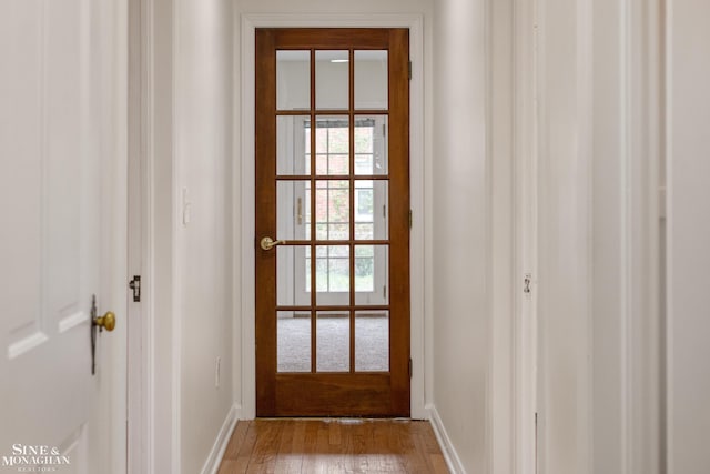 doorway with baseboards and wood finished floors