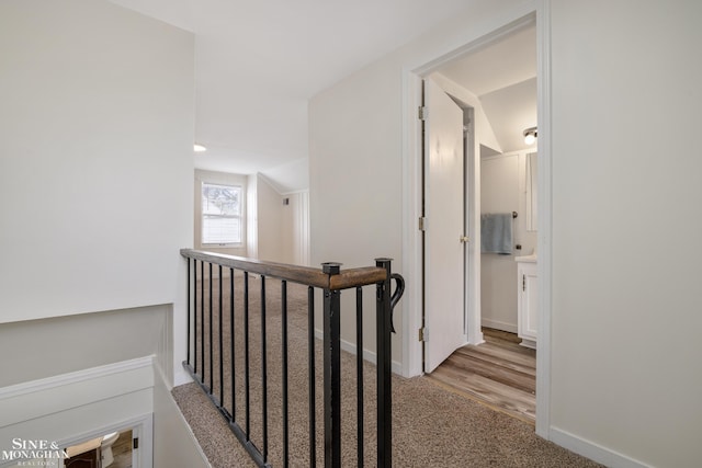 hall featuring an upstairs landing, vaulted ceiling, carpet, and baseboards