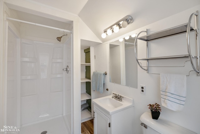 bathroom with a shower stall, toilet, vanity, lofted ceiling, and wood finished floors