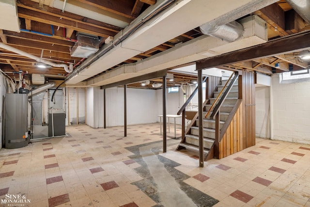 below grade area featuring tile patterned floors, water heater, and stairs