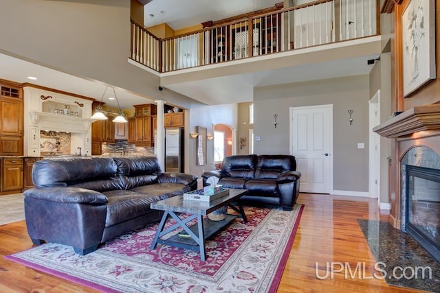 212 S 1st Ave, Escanaba, MI 49829 - living room with a premium fireplace, light wood-style flooring, a high ceiling, baseboards, and arched walkways