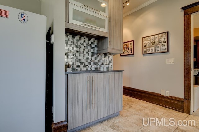 212 S 1st Ave, Escanaba, MI 49829 - kitchen featuring crown molding, tasteful backsplash, light tile patterned flooring, freestanding refrigerator, and dark countertops
