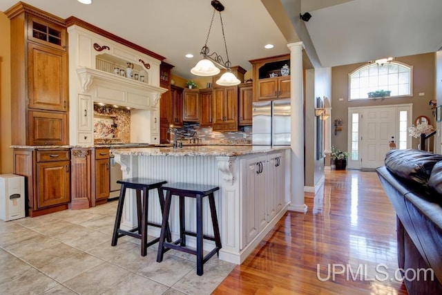 212 S 1st Ave, Escanaba, MI 49829 - kitchen featuring stainless steel fridge, light stone countertops, brown cabinets, range, and recessed lighting