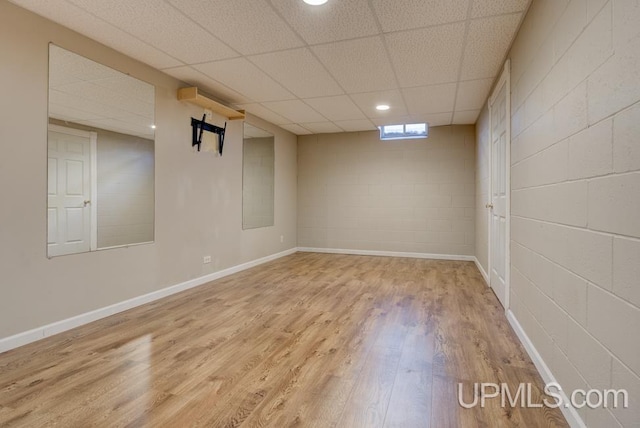 212 S 1st Ave, Escanaba, MI 49829 - below grade area featuring wood finished floors, a drop ceiling, concrete block wall, and baseboards