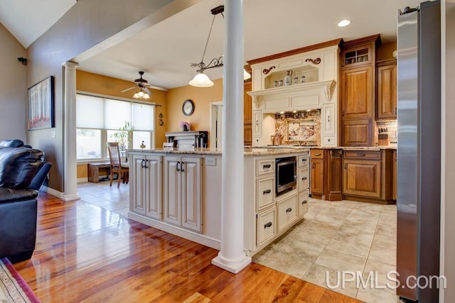 212 S 1st Ave, Escanaba, MI 49829 - kitchen featuring decorative columns, freestanding refrigerator, ceiling fan, open floor plan, and light stone countertops