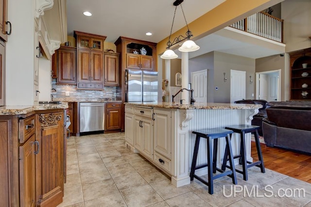 212 S 1st Ave, Escanaba, MI 49829 - kitchen featuring stainless steel appliances, open floor plan, a breakfast bar area, light stone counters, and brown cabinets