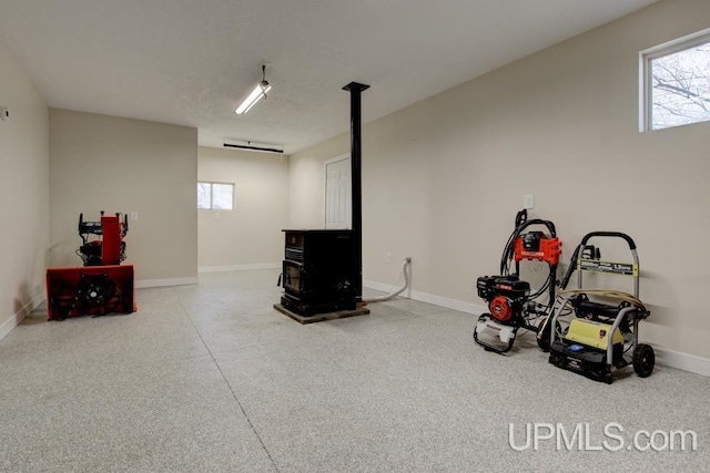 212 S 1st Ave, Escanaba, MI 49829 - below grade area featuring a wood stove, healthy amount of natural light, and baseboards