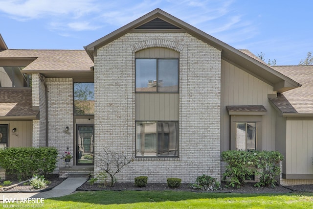 view of front of home with brick siding and a shingled roof