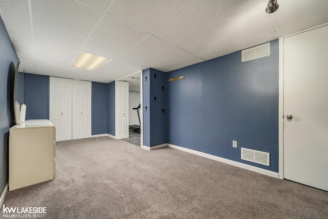 finished below grade area with carpet, baseboards, and a paneled ceiling