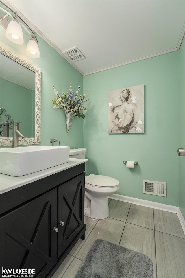 bathroom with toilet, vanity, crown molding, and baseboards