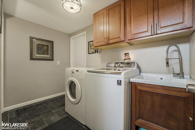 laundry room featuring washer and clothes dryer, cabinet space, baseboards, and dark tile patterned flooring
