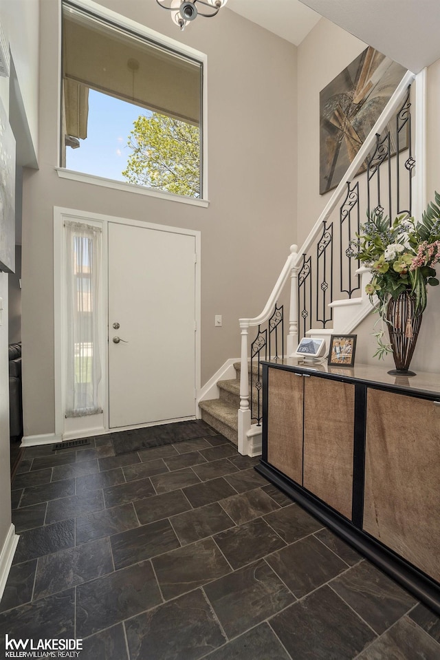foyer featuring stairway, a high ceiling, and baseboards