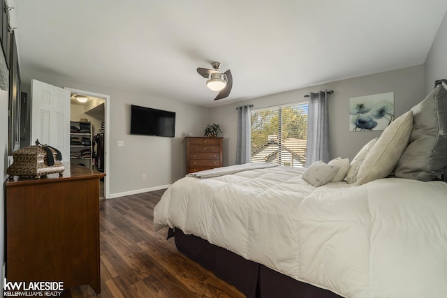 bedroom featuring dark wood finished floors, baseboards, a spacious closet, ceiling fan, and a closet