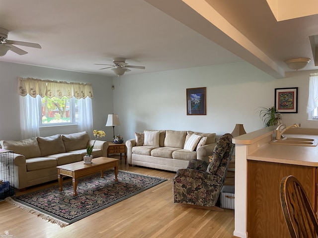 living area with ceiling fan and light wood finished floors