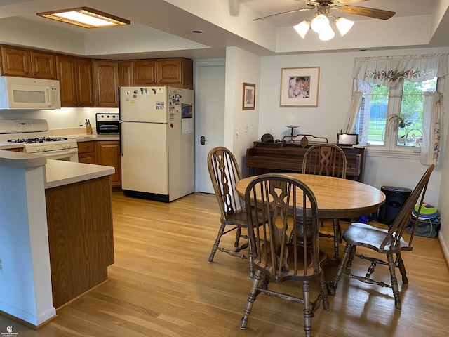 dining area featuring light wood-type flooring, a ceiling fan, and baseboards