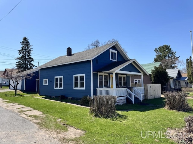 437 N Main St, Lanse, MI 49946 - view of front of house with covered porch, a chimney, and a front yard
