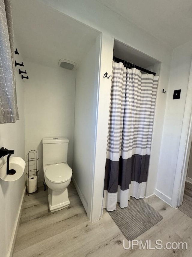 437 N Main St, Lanse, MI 49946 - full bath with wood finished floors, toilet, baseboards, and a shower with shower curtain