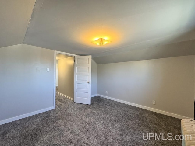 437 N Main St, Lanse, MI 49946 - additional living space with dark colored carpet, lofted ceiling, and baseboards