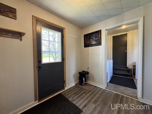 437 N Main St, Lanse, MI 49946 - doorway to outside with dark wood-style floors, baseboards, ornamental molding, and a decorative wall