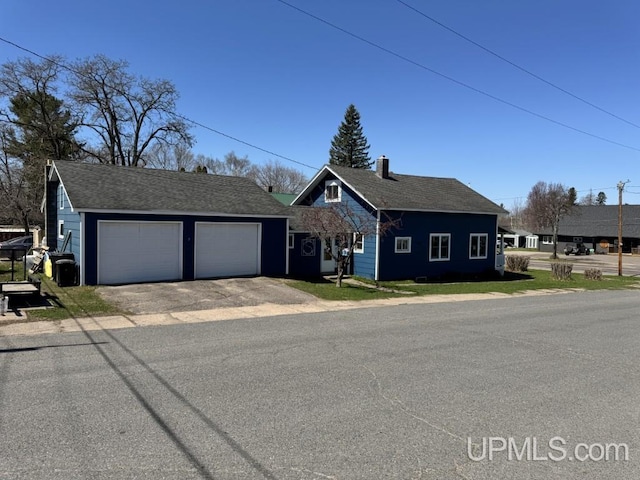 437 N Main St, Lanse, MI 49946 - view of front of home featuring a garage, driveway, and a chimney