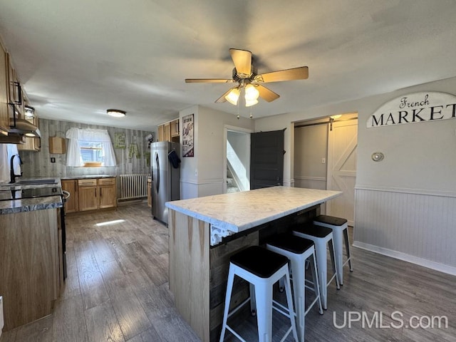 437 N Main St, Lanse, MI 49946 - kitchen featuring a barn door, stainless steel refrigerator with ice dispenser, dark wood-style flooring, wainscoting, and ceiling fan