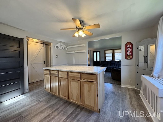 437 N Main St, Lanse, MI 49946 - kitchen featuring a barn door, dark wood-type flooring, a ceiling fan, wainscoting, and a kitchen island