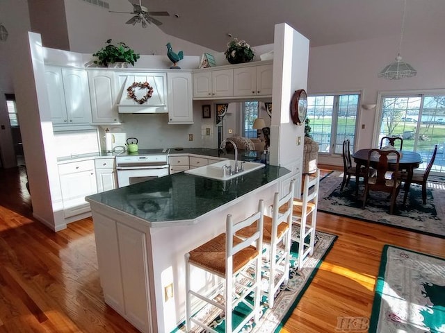 1726 Berkshire Dr, Gladwin, MI 48624 - kitchen featuring electric stove, a sink, a peninsula, a breakfast bar area, and light wood finished floors
