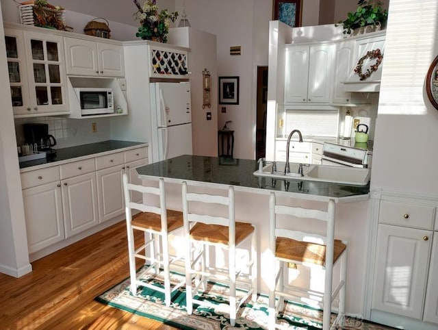 1726 Berkshire Dr, Gladwin, MI 48624 - kitchen with white appliances, decorative backsplash, a breakfast bar, a peninsula, and white cabinetry