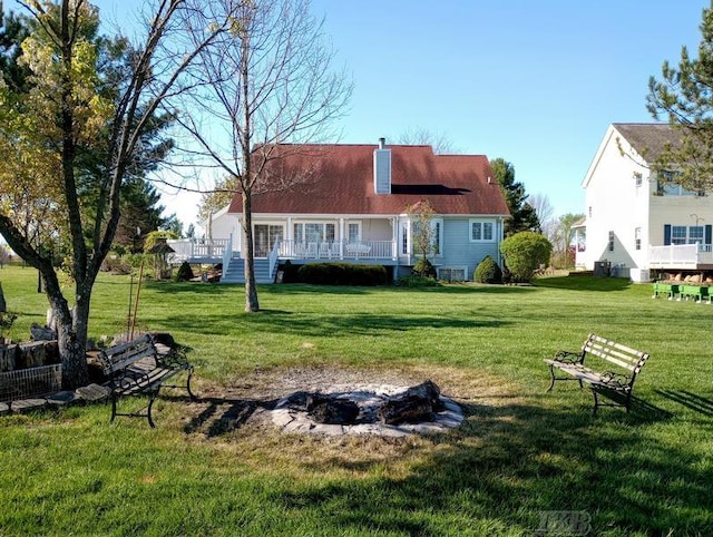 1726 Berkshire Dr, Gladwin, MI 48624 - back of house featuring a lawn, a chimney, a fire pit, and a wooden deck