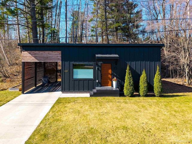 218 W Fairbanks St, Marquette, MI 49855 - mid-century modern home featuring board and batten siding, a front yard, and concrete driveway